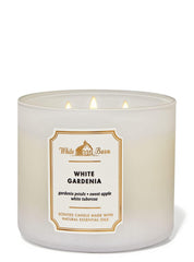 Lit Bath & Body Works White Barn candle emits warm glow with White Gardenia.