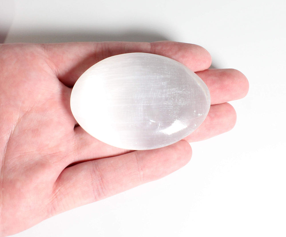 MINERALUNIVERSE natural white selenite palm stone close-up for calming rituals.
