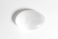 MINERALUNIVERSE selenite palm stone close-up highlighting smooth surface.