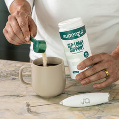 A glass of prepared Supergut GLP-1 Daily Support drink with light, smooth texture