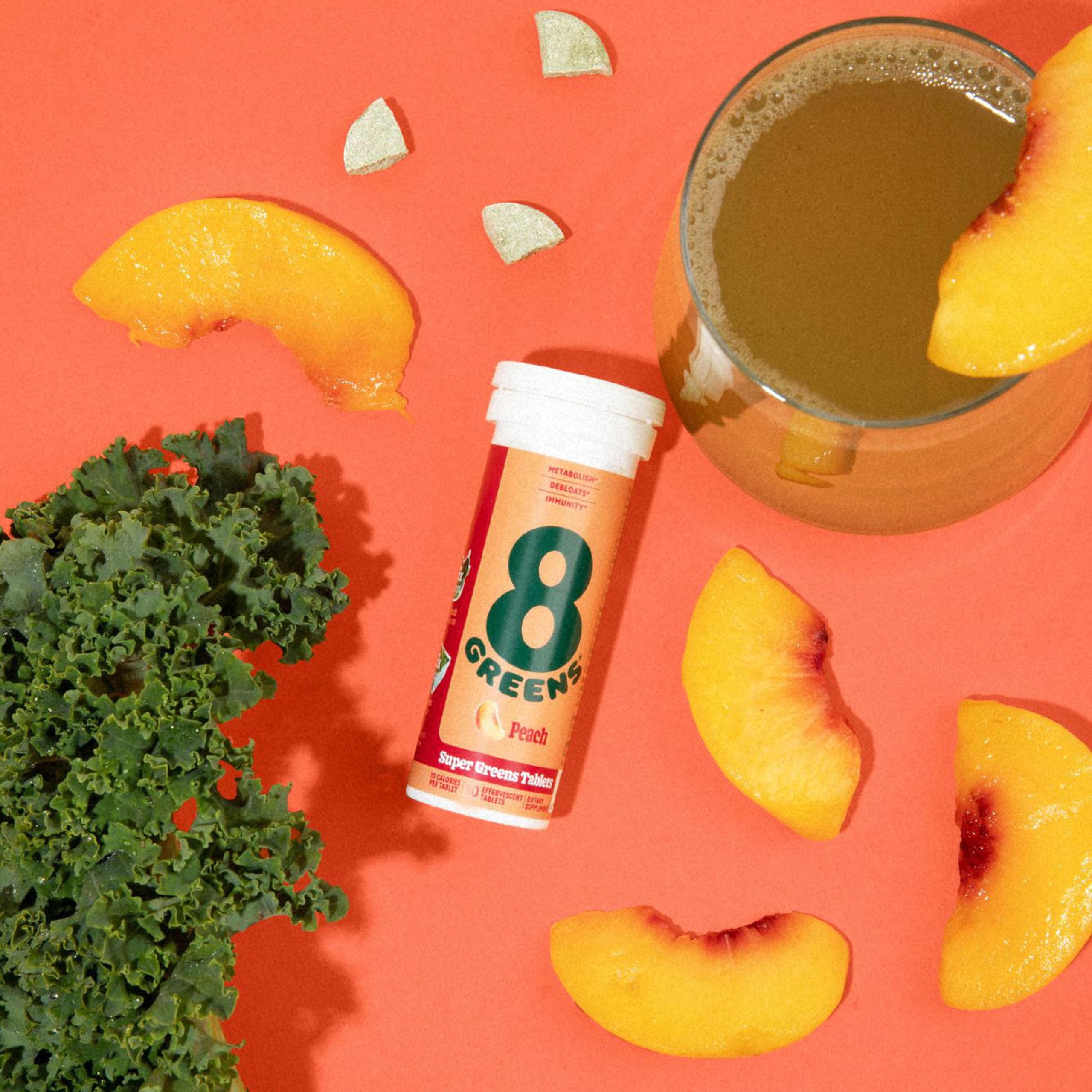 8Greens peach-flavor tablets in a glass with straw for easy hydration.