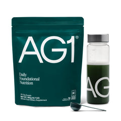 AG1 greens powder bottle with scoop on counter for daily nutrition and gut support.