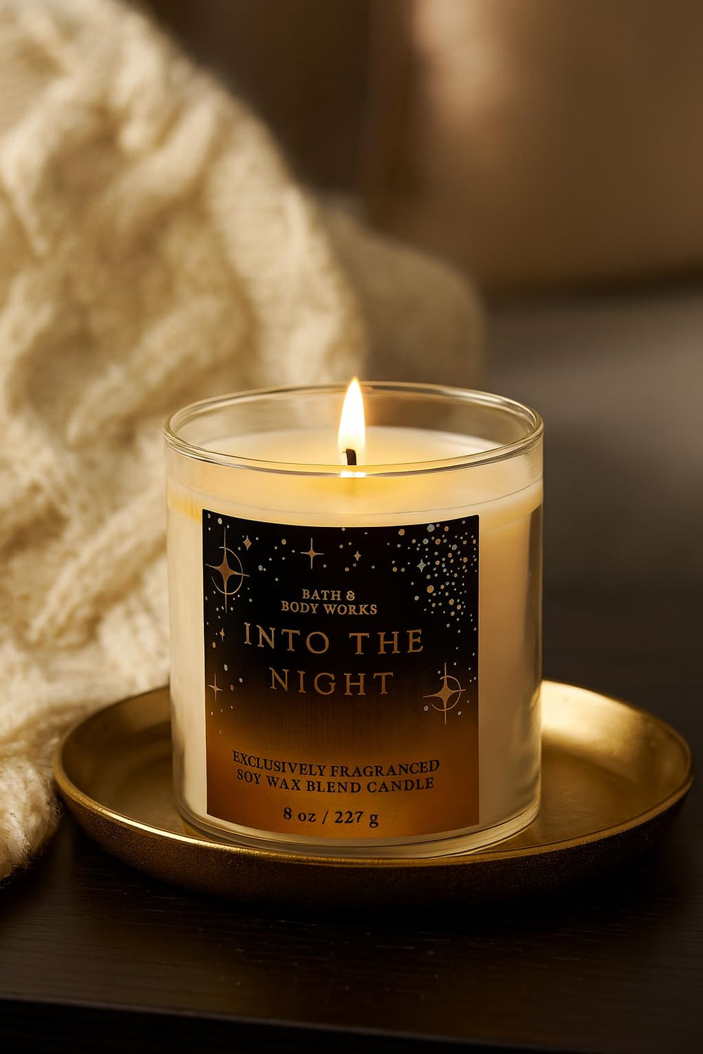 Bath & Body Works Into The Night candle on a table casts a soft, inviting glow.