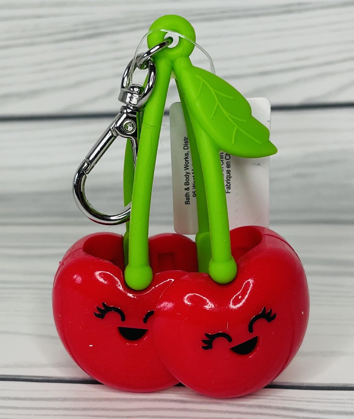Bath & Body Works red-cherries PocketBac holder on bag demonstrates convenient travel sanitizing