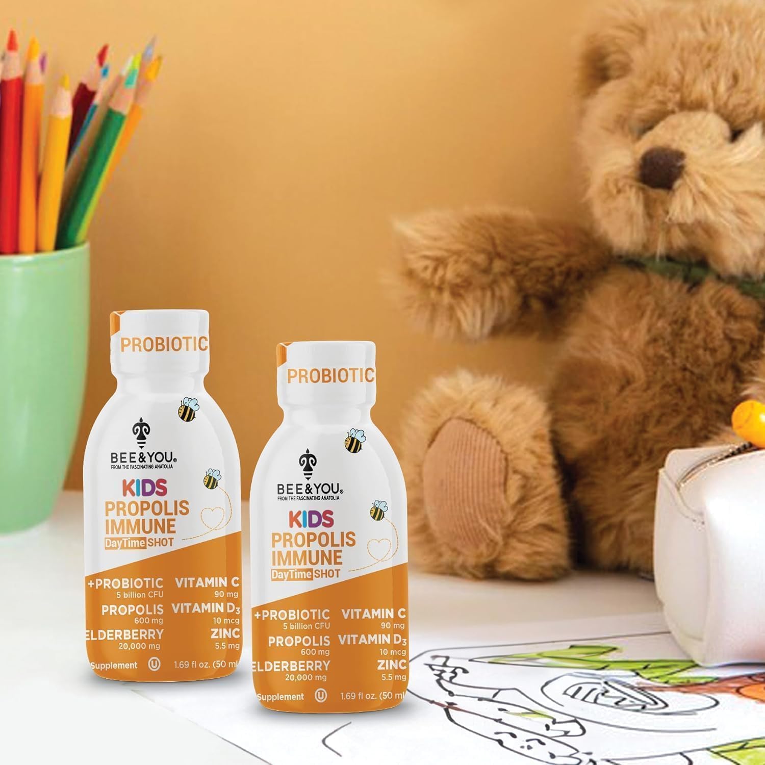 Glass of water beside Bee & You Kids Propolis Immune Shot bottle