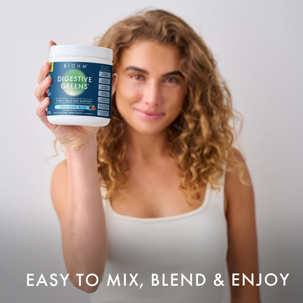 BIOHM Digestive Greens glass with Berry powder dissolving, ready to drink.