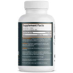 A hand holds Bronson Biotin 5,000 mcg mini tablet for convenient daily use.