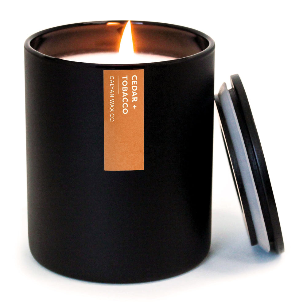 Calyan Cedar & Tobacco candle jar with cedar notes and warm glow.