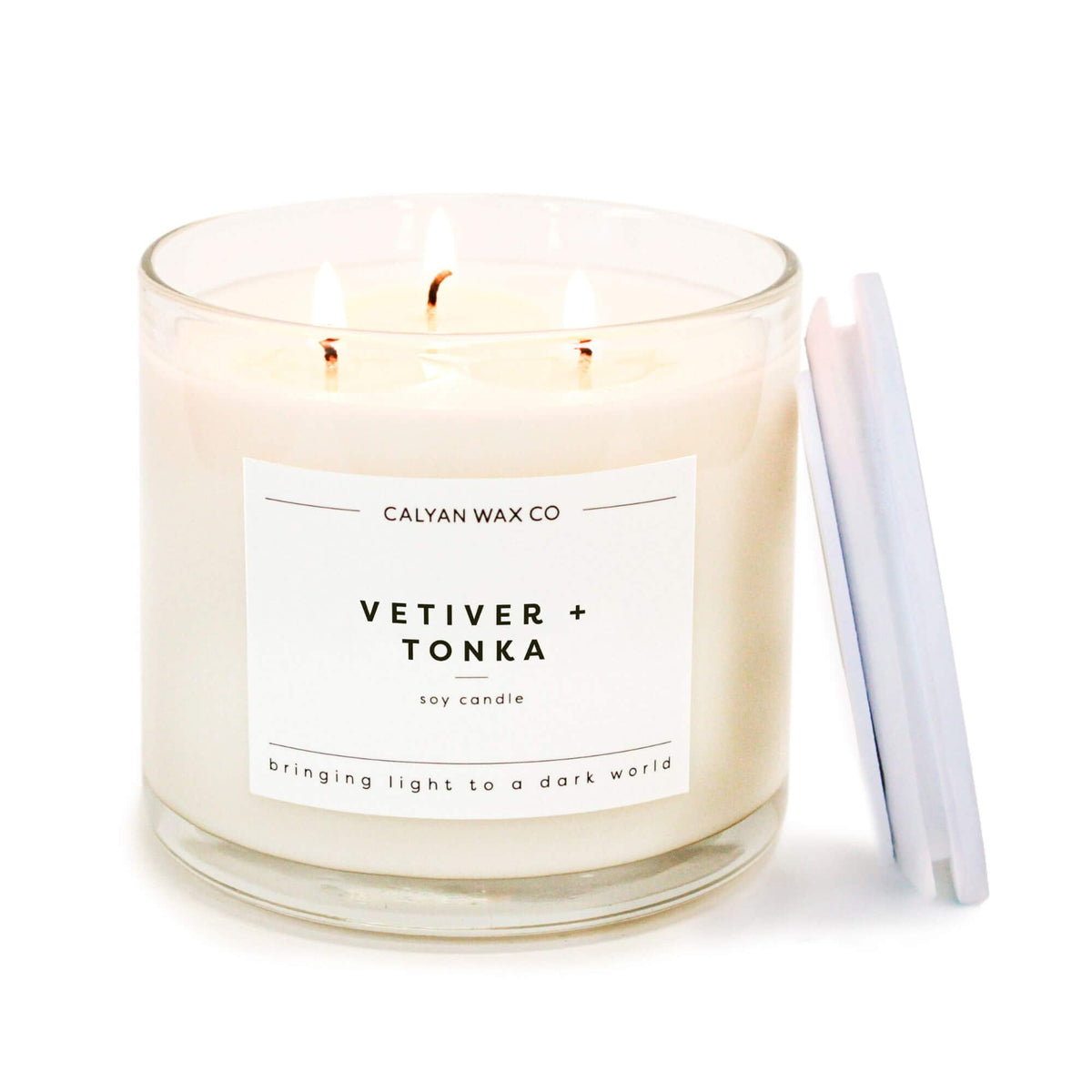 Calyan Wax Co Vetiver & Tonka 3 Wick jar glows, filling a room with cozy aroma.