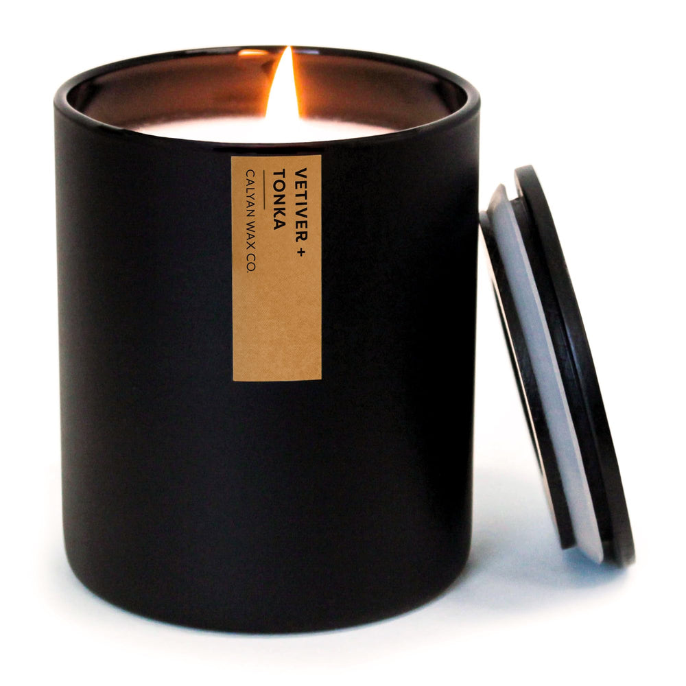 Calyan Wax Co Vetiver & Tonka candle in a black tumbler emits warm ambient light