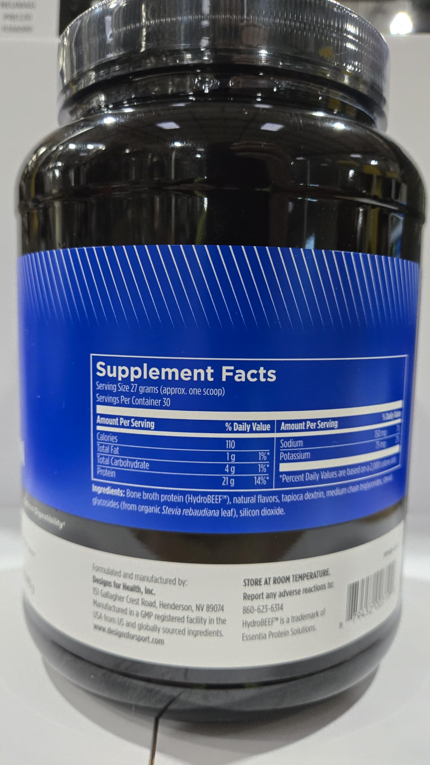 Designs for Sport vanilla protein powder bottle and pouring setup on countertop.