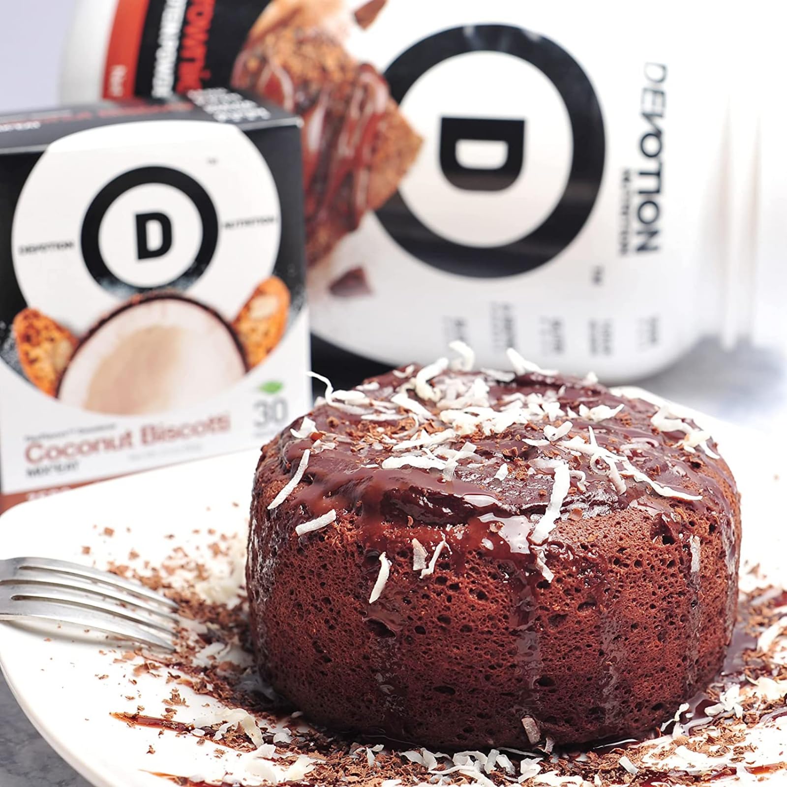 Devotion Nutrition Brownie Batter packets on a kitchen counter with measuring spoon.