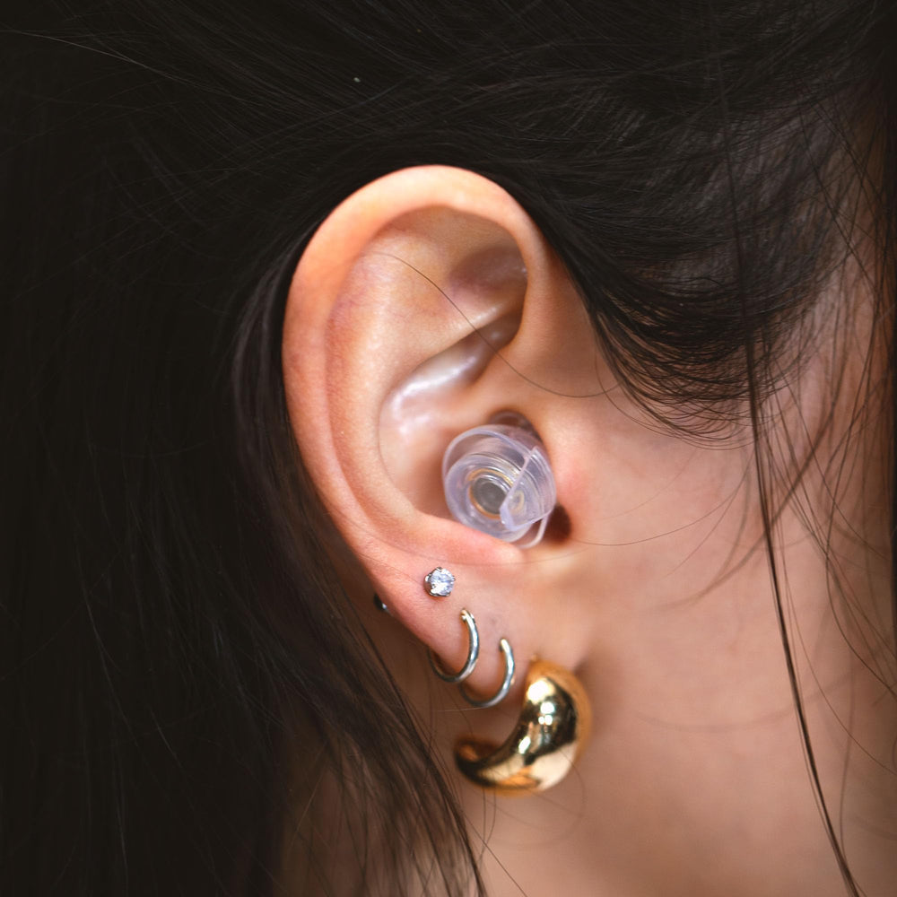 Bedroom scene with Eargasm earplugs offering gentle sleep-time noise reduction.