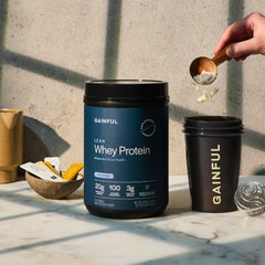 Gainful Lean Whey scoop beside the tub for precise portions.