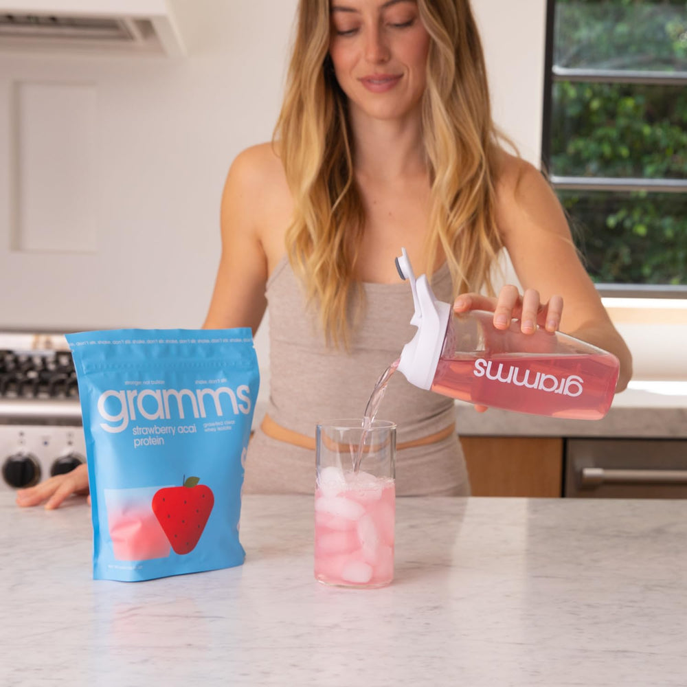 GRAMMS Clear Protein Water Glass with strawberry acai, refreshing post-workout option.