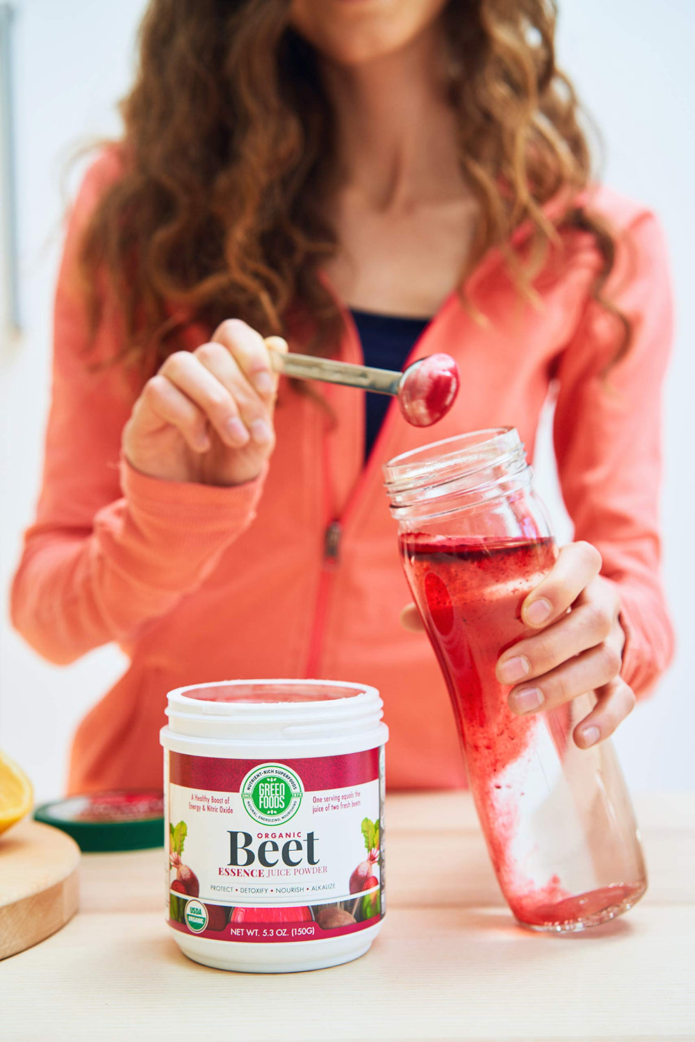 Green Foods Beet Essence OG2 being poured into juice, vivid color boost