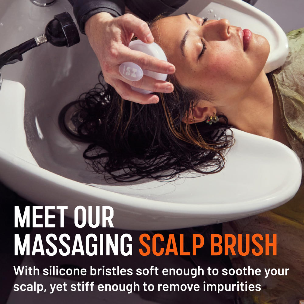 Hairstory Massaging Scalp Brush in hand for even product distribution.