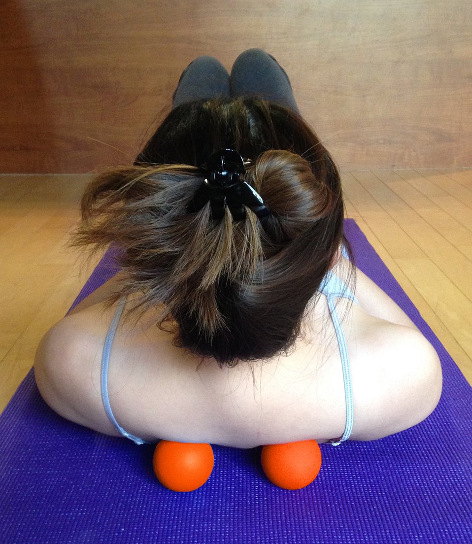 Kieba lacrosse balls orange on yoga mat for targeted muscle release anywhere.