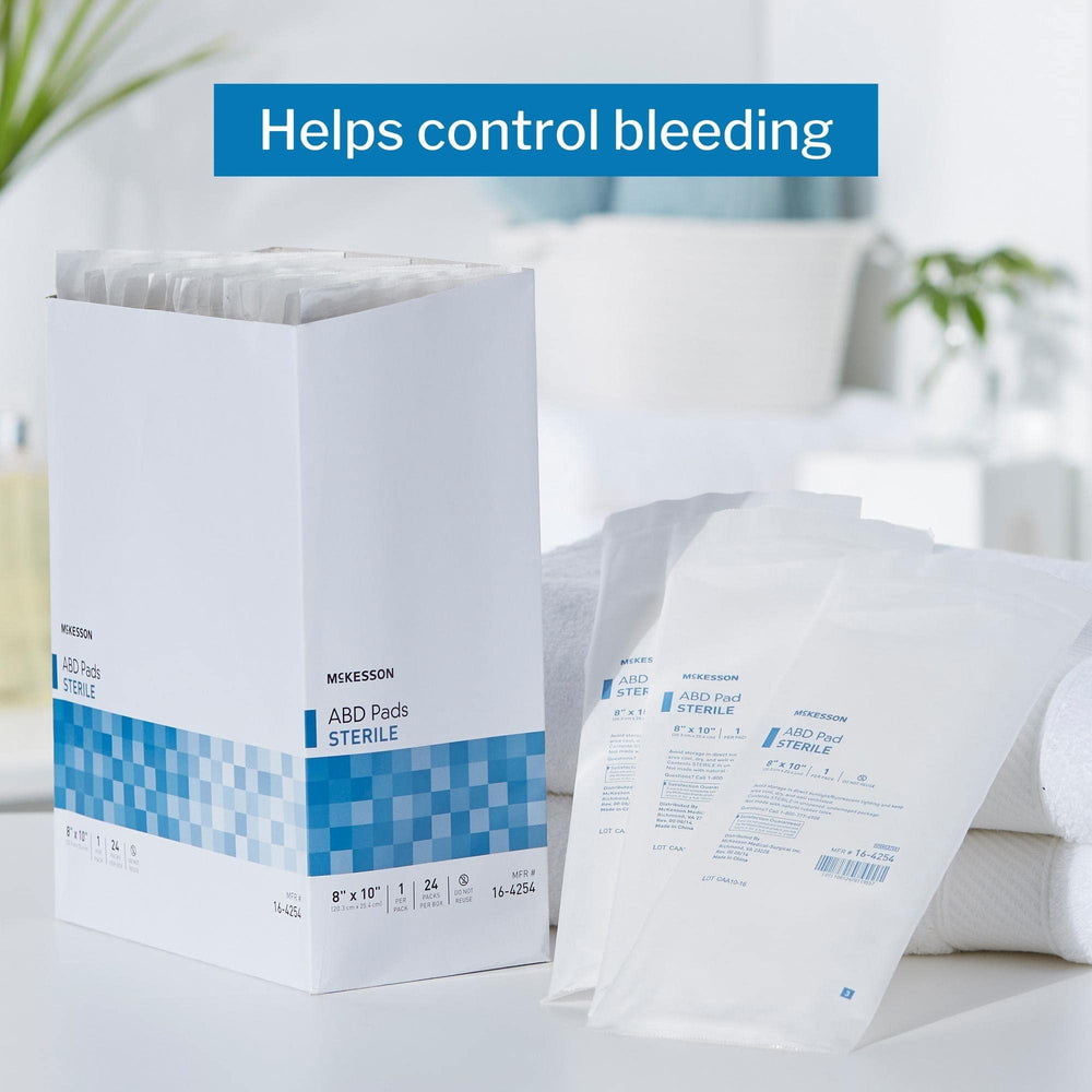 Box of McKesson 24-count ABD pads emphasizes absorbent drainage management for abdominal wounds.