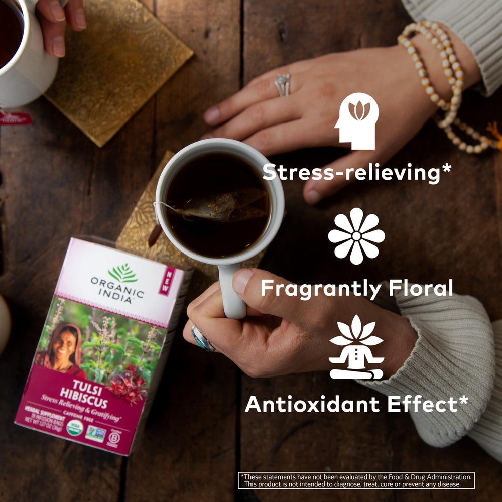Pouring hot water into a mug reveals vibrant hibiscus and tulsi infusion.