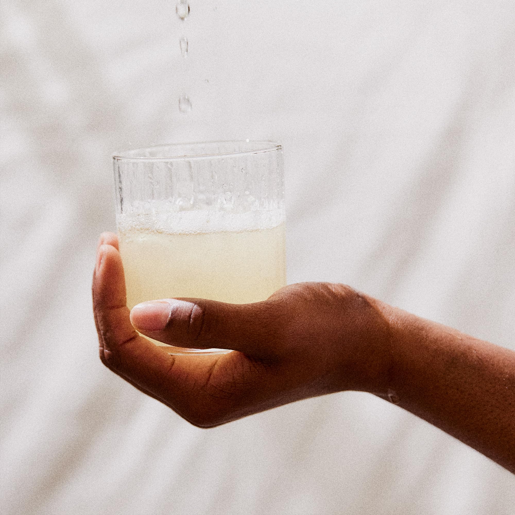Stirring Perelel Hydration Support into water for a citrus sip.