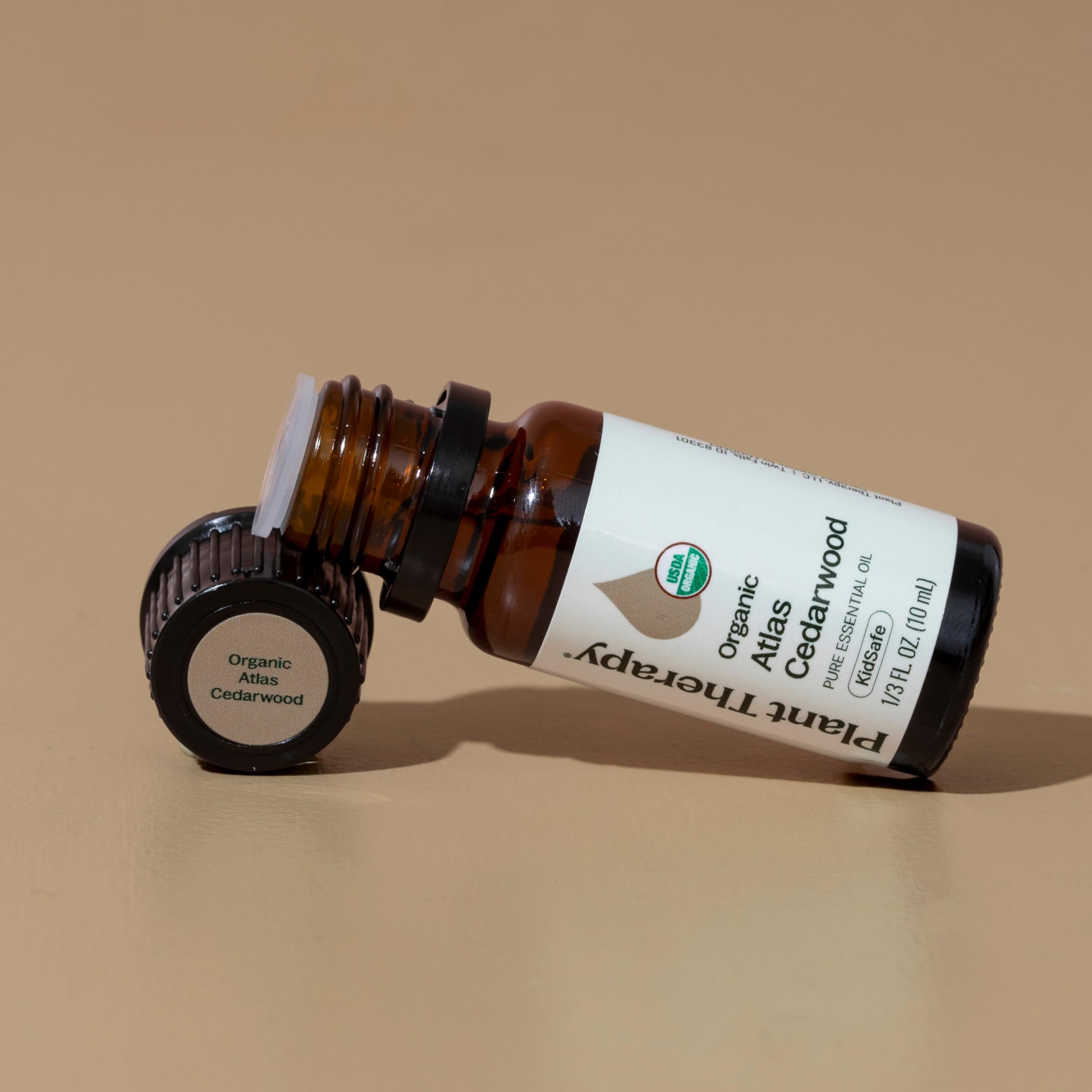 Plant Therapy Atlas Cedarwood oil on wooden background conveys natural sourcing.