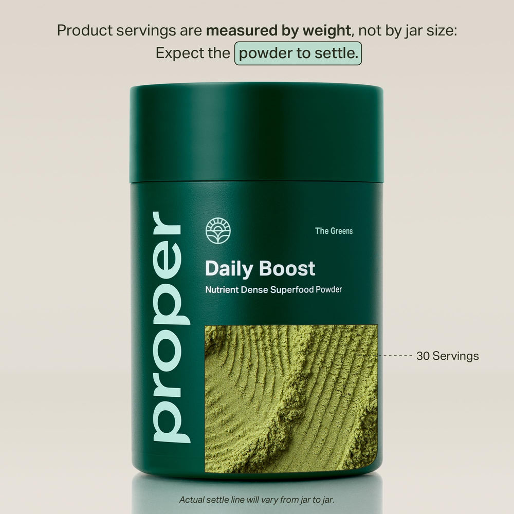 Scoop of Proper Greens Daily Boost dissolving in water for quick mixing.