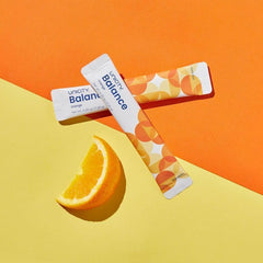 Unicity Balance Natural Orange sachets dissolving in water for steadier energy.