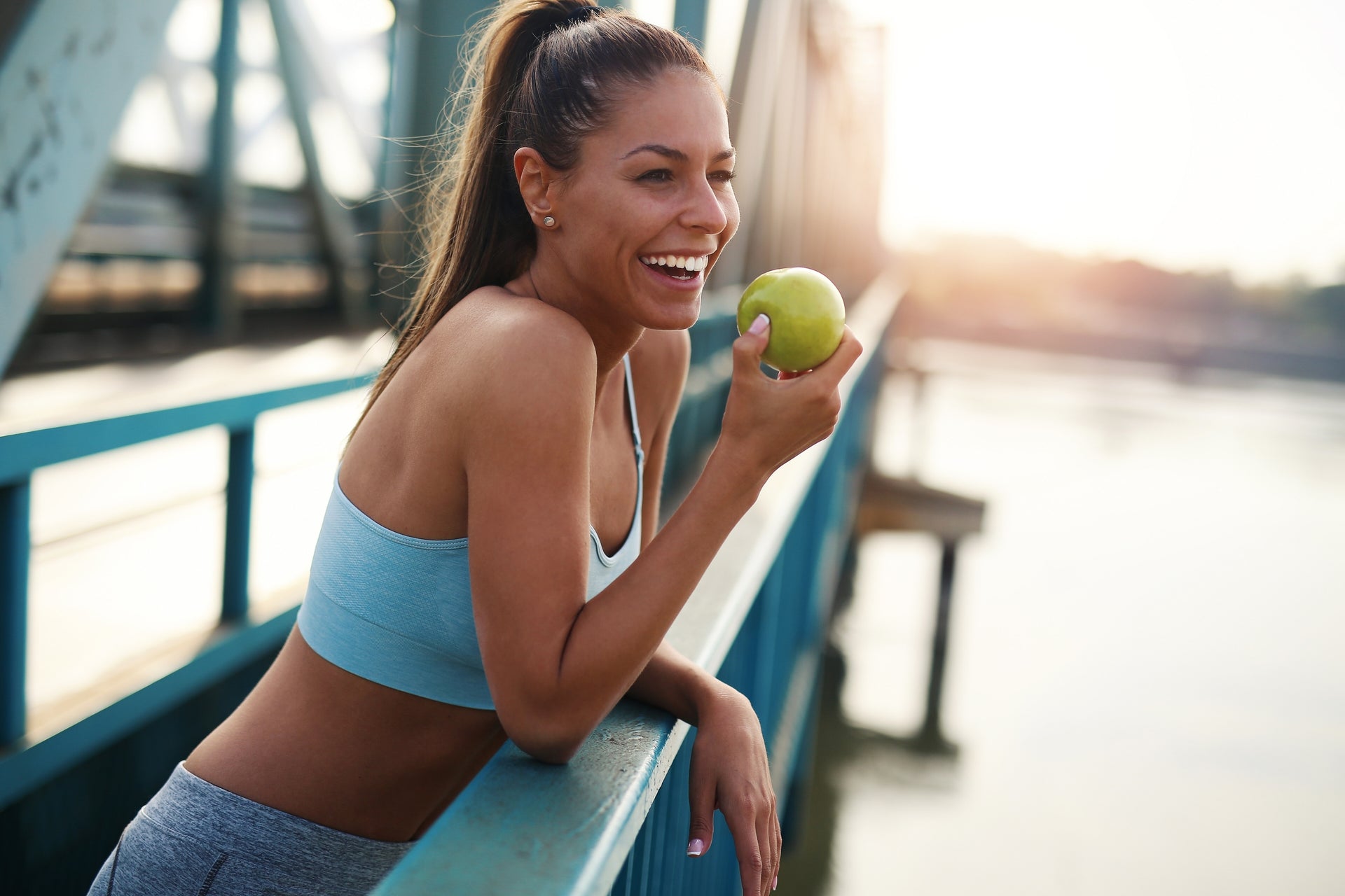 Woman holding an apple by a bridge