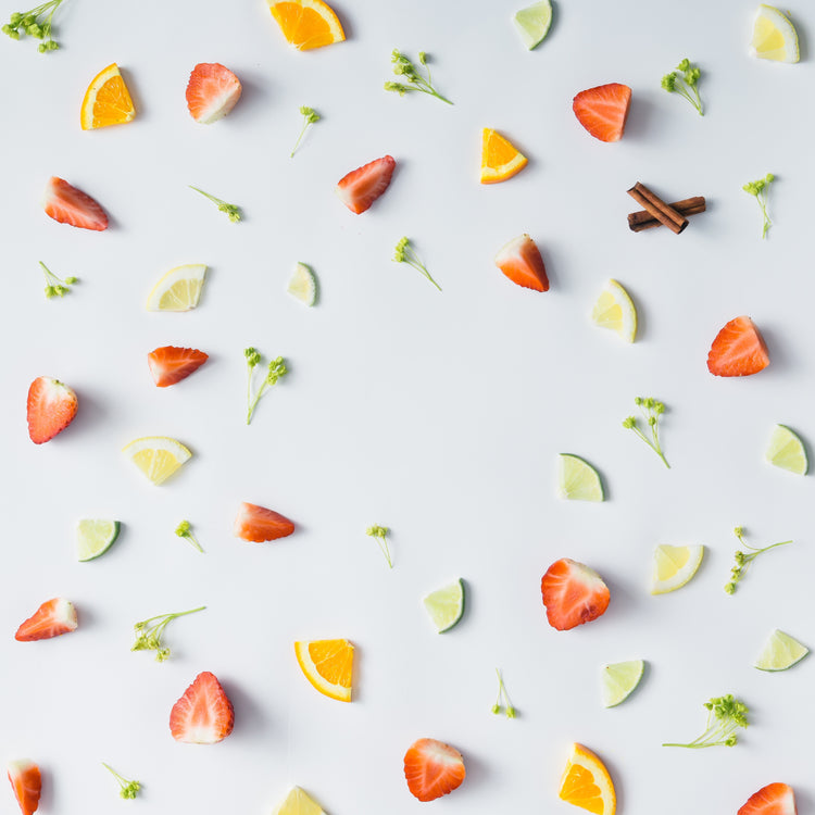 Fruit slices including strawberries, oranges, and lemons on a light gray background